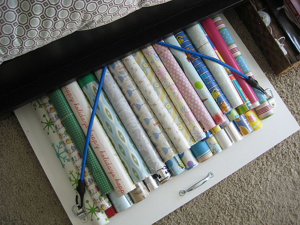 Organize your wrapping paper under bed with a board with bungee cords. 