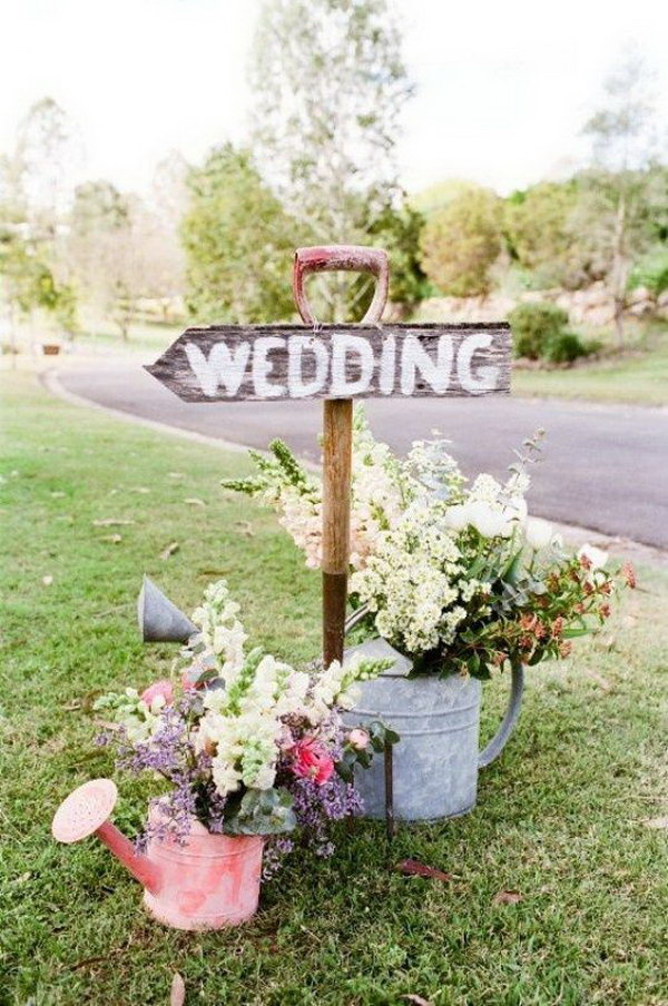 Rustic Wedding Wooden Sign. Finish off your rustic wedding theme with this wooden wedding sign to point the right direction for your guests. Prop it up with pitch for or garden shovel. It’s fantastic to use watering cans as flower holders to add up some decorations. 