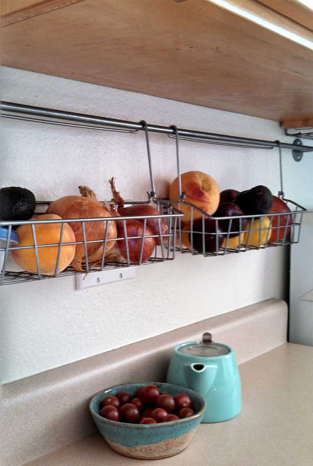 Hang some wire baskets on a rod that fixed on the kitchen backsplash. 